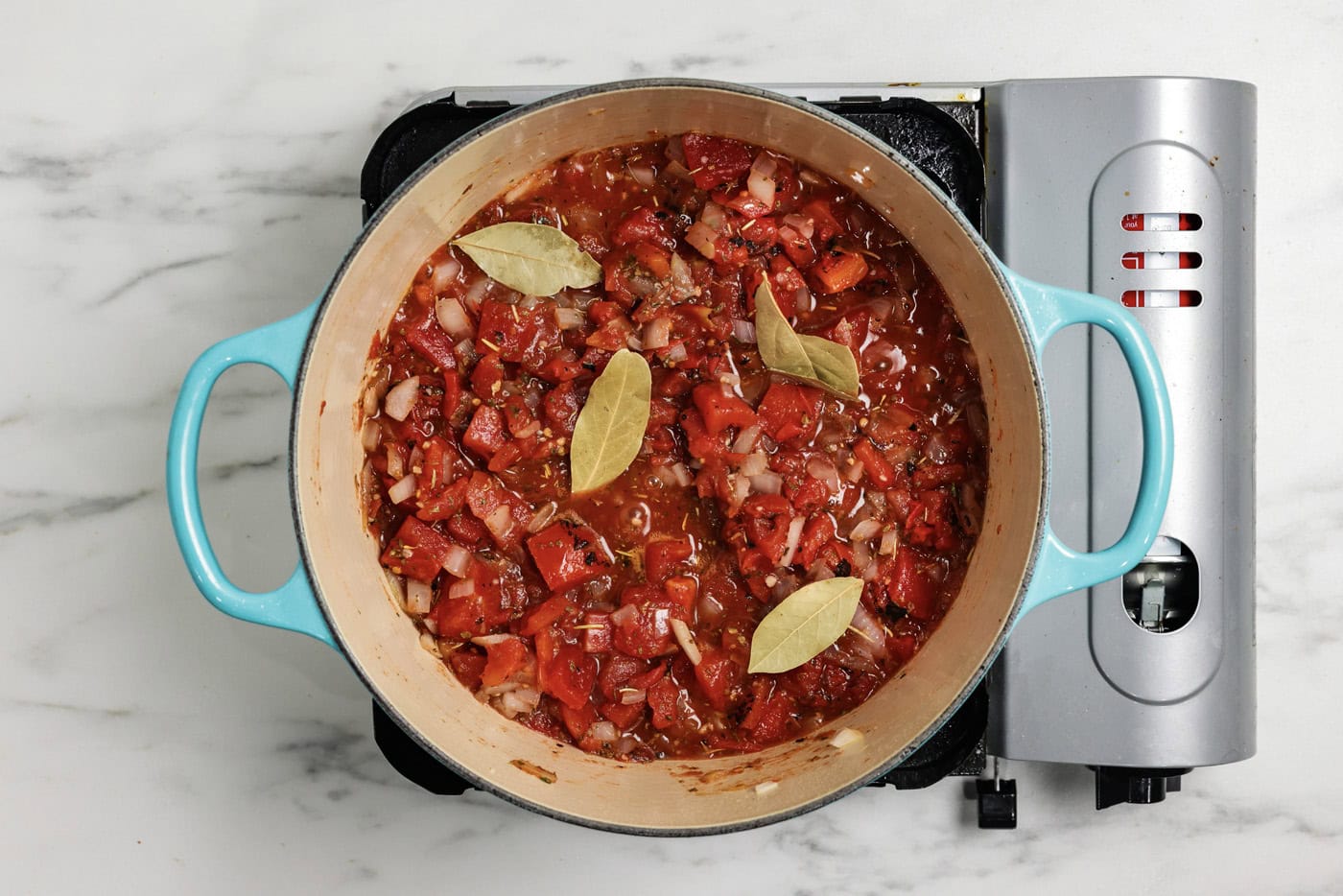 Basil added to pot with tomatoes and seasonings