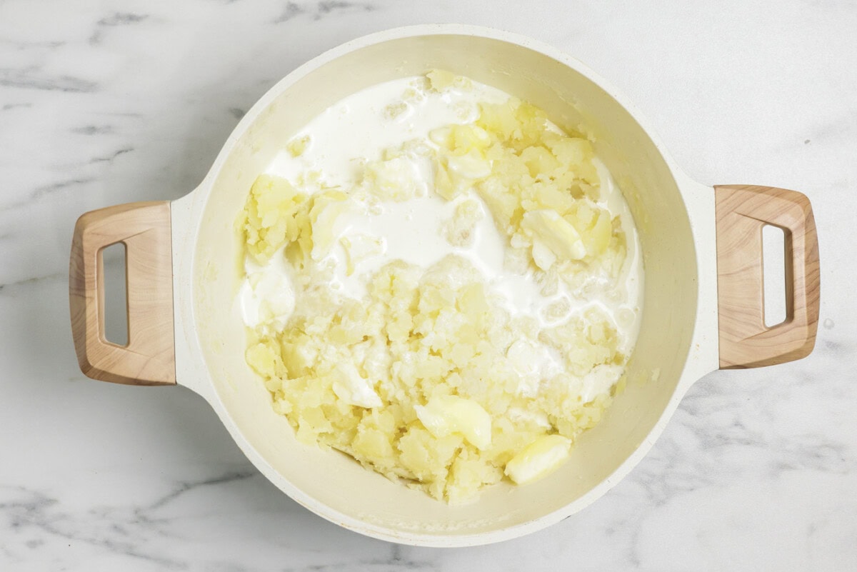 Heavy cream and butter added to stockpot with mashed potatoes