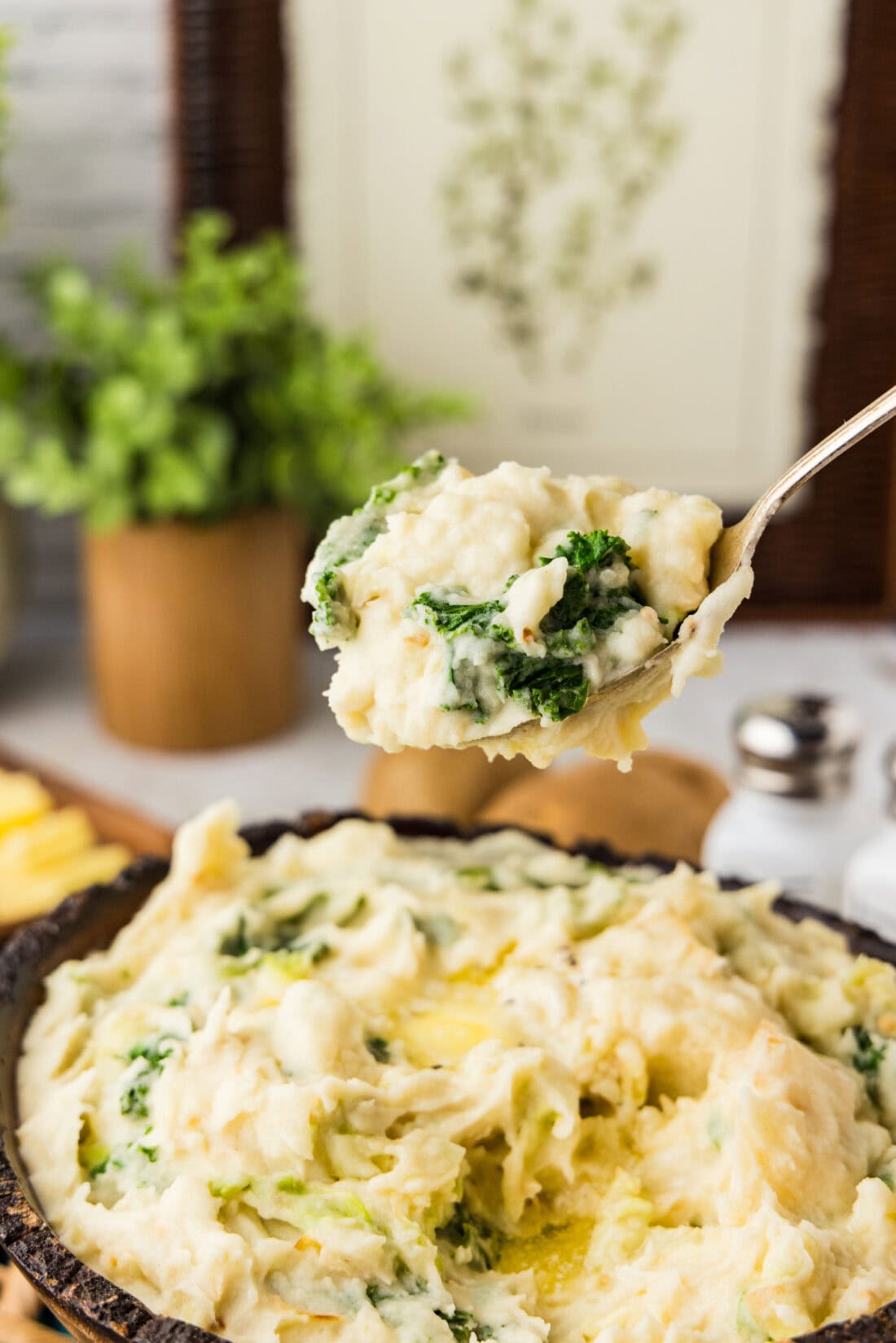 Spoonful of Colcannon (Irish Mashed Potatoes) held above the bowl of Colcannon 