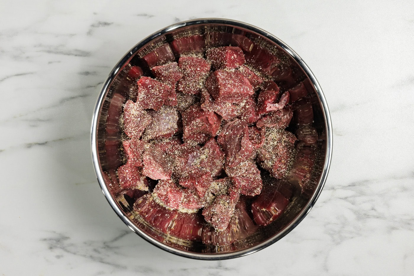 Cubed sirloin beef in a bowl with seasonings