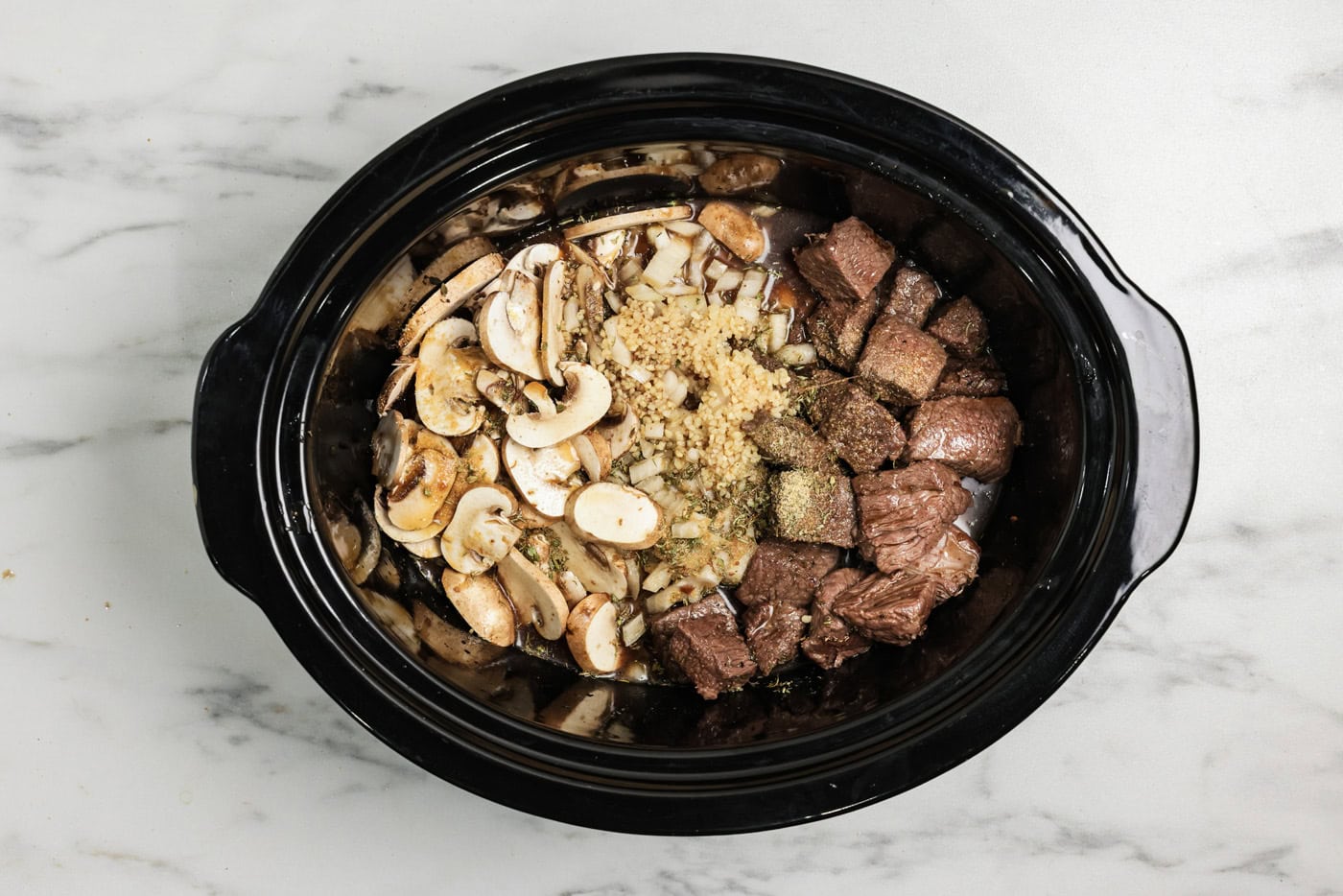 Browned sirloin cubes, onions, and mushrooms along with seasonings added to crock