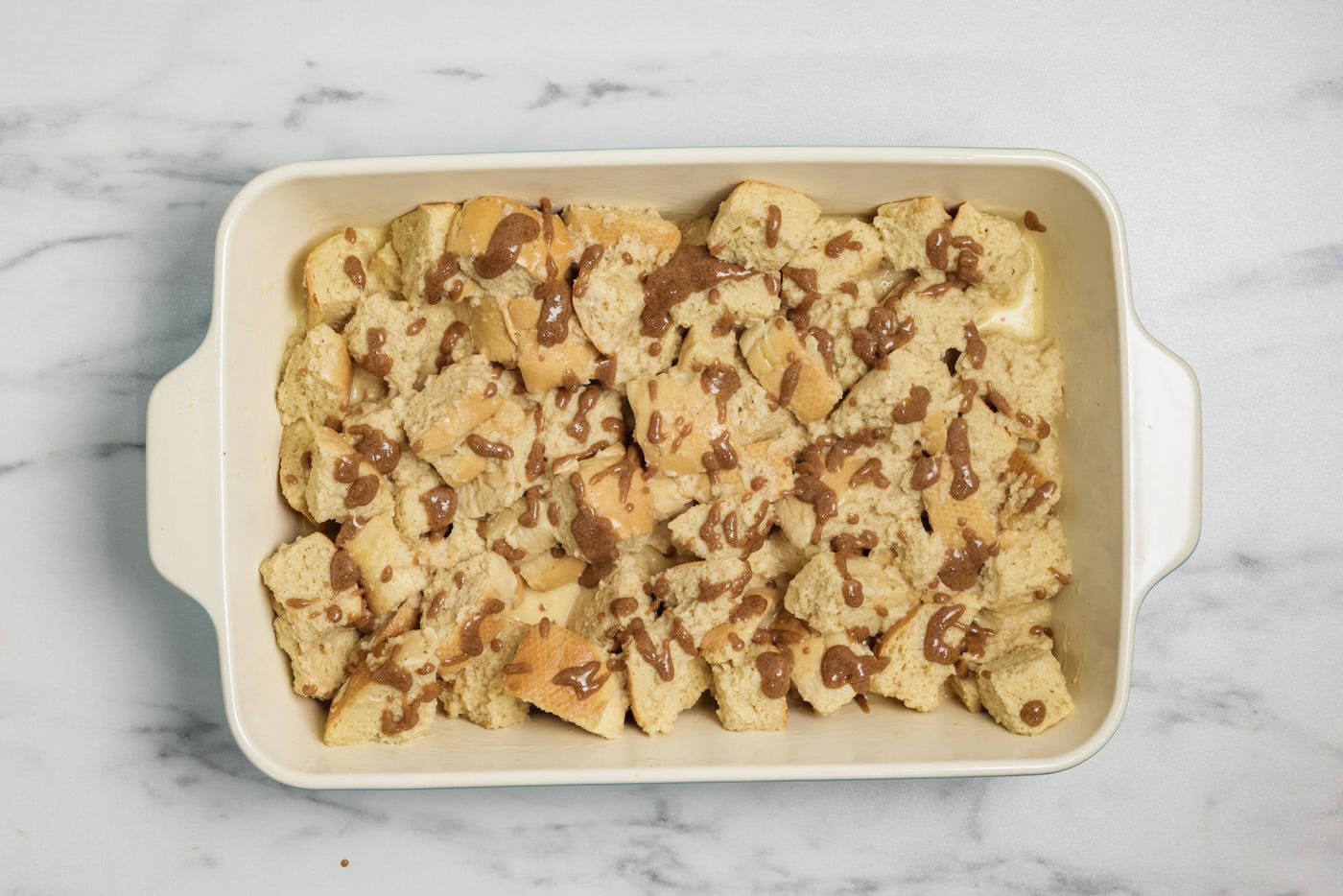 Cinnamon butter mixture drizzled over French toast casserole in a dish