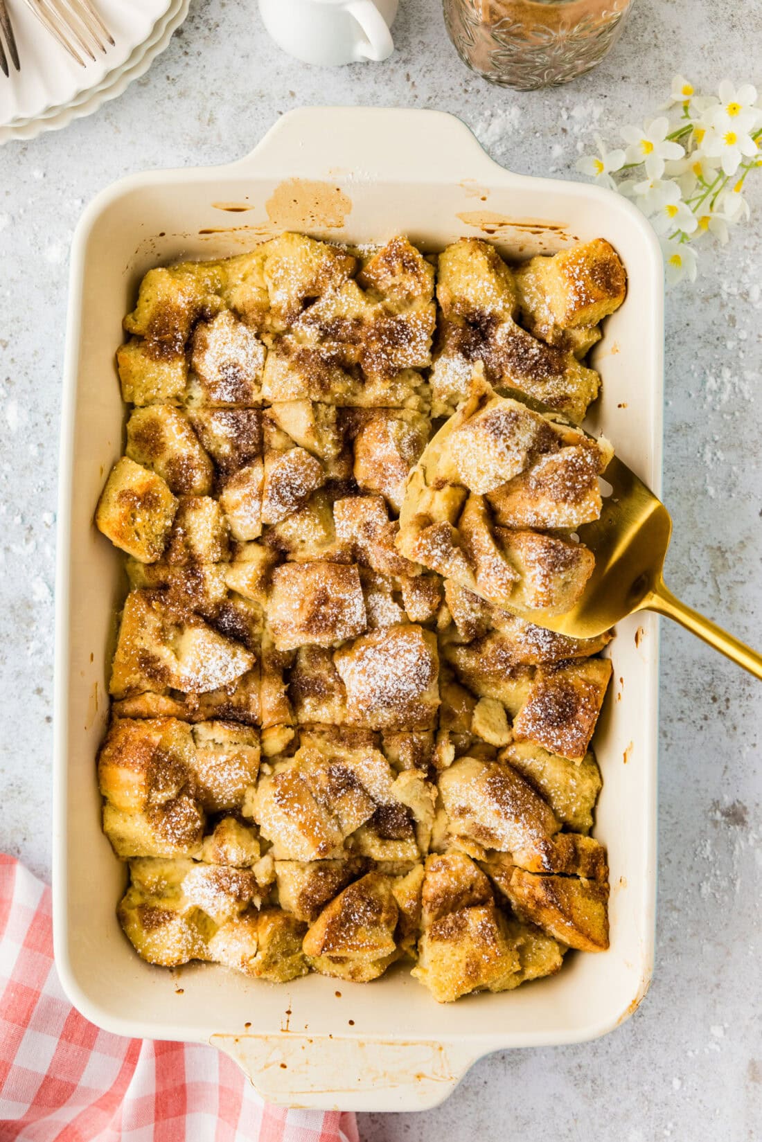 Spatula holding up a slice of French Toast Casserole above the baking dish of French Toast Casserole 