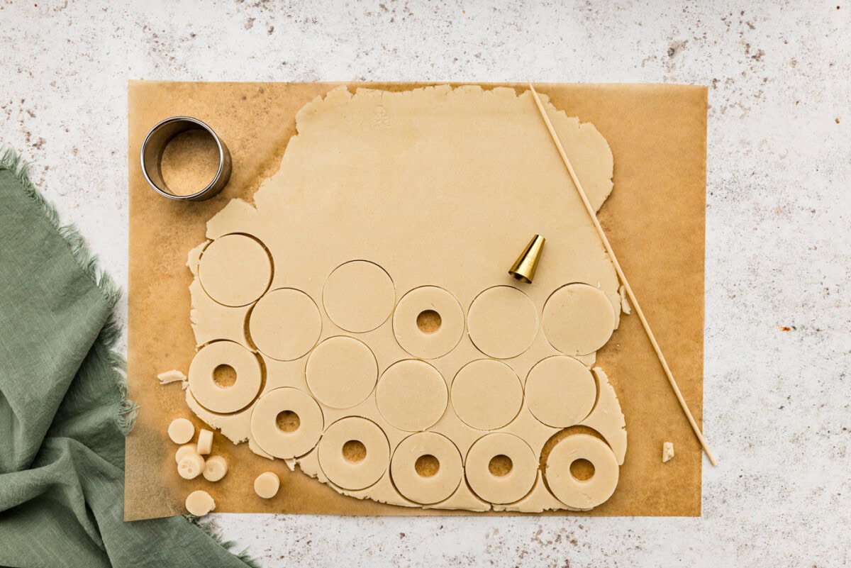 Small end of a piping tip piercing a hole through cookie dough circles
