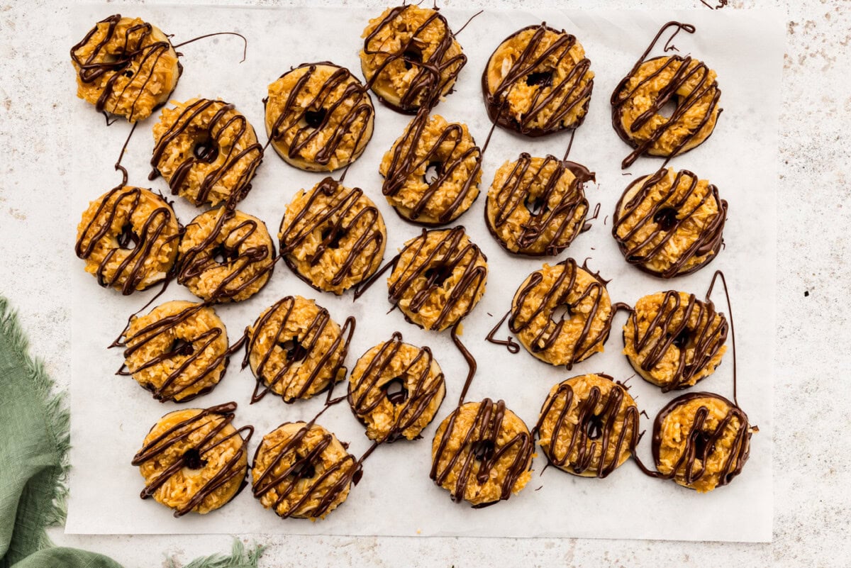 Chocolate drizzled over homemade Samoas on parchment paper