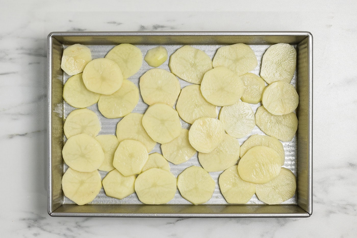 Thinly sliced potato rounds in a baking pan