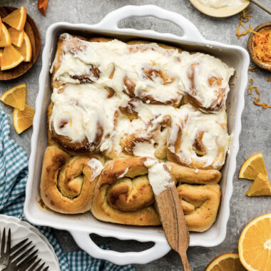 Frosting being added to a pan of Quick Orange Rolls
