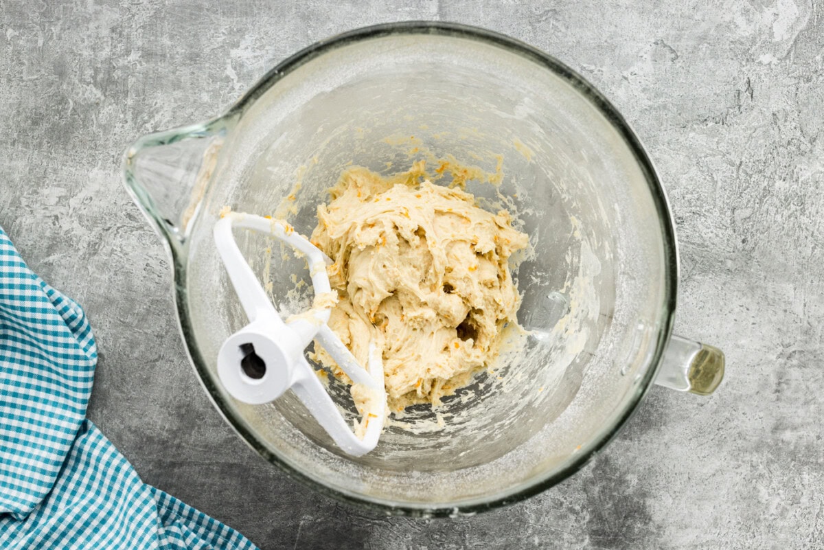Orange roll dough in a stand mixer bowl with paddle attachment