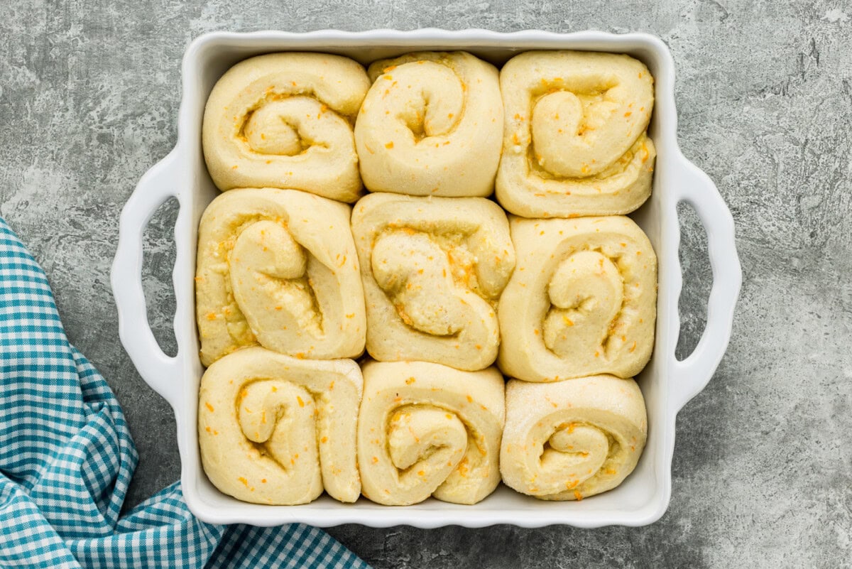 Orange roll dough in a baking dish doubled in size