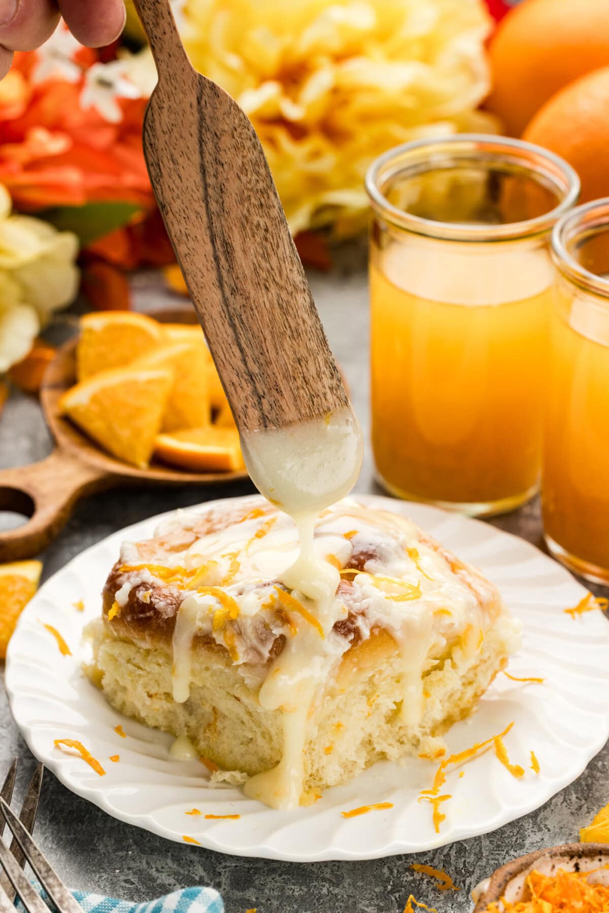 Frosting being drizzled over a Quick Orange Roll on a plate