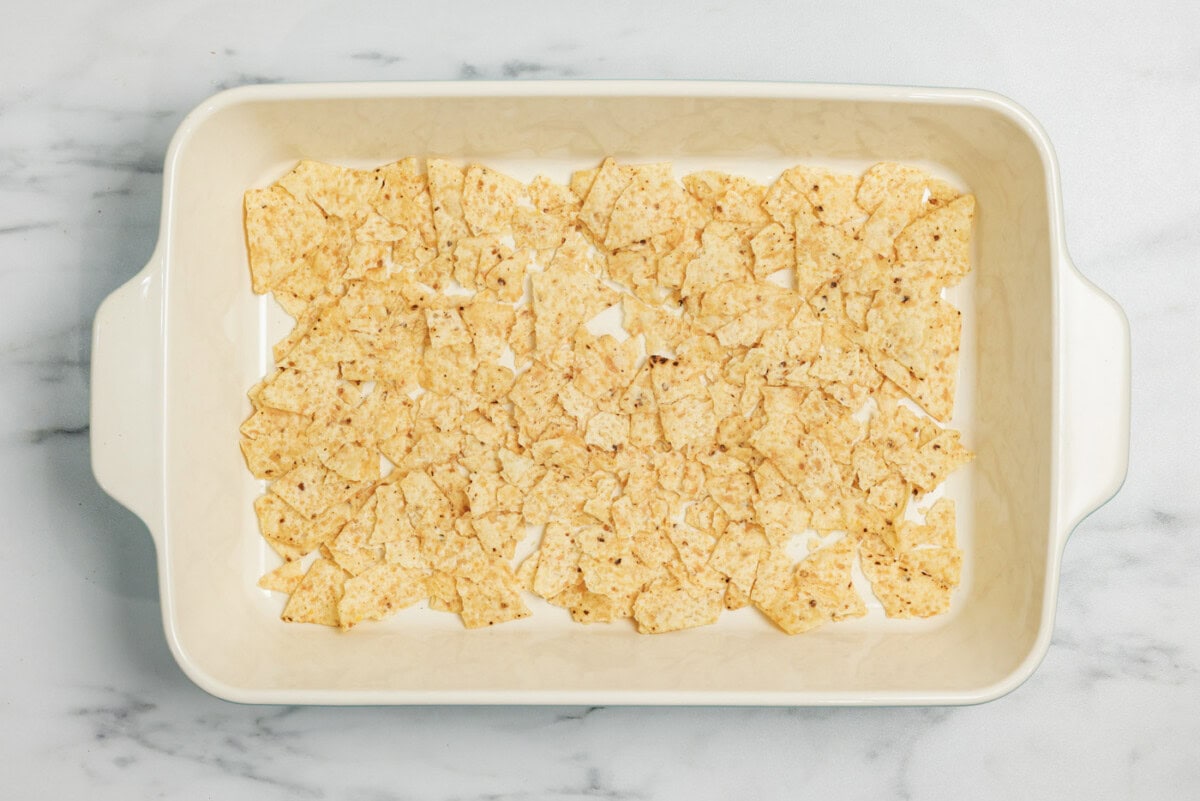 Slightly crumbled tortilla chips on bottom of a baking dish