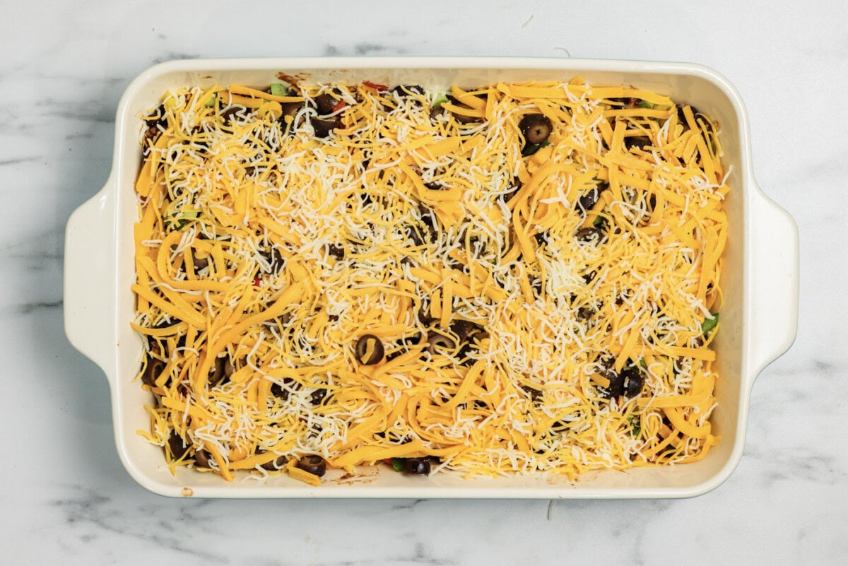 Shredded cheese on top of taco casserole in a dish