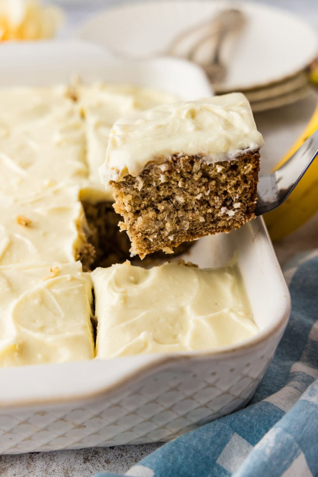 spatula lifting a slice of frosted banana cake