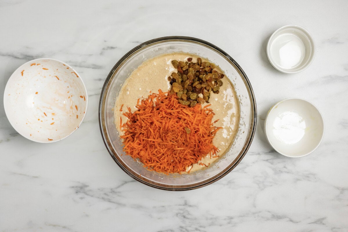 shredded carrots and golden raisins added to spice cake batter in a bowl