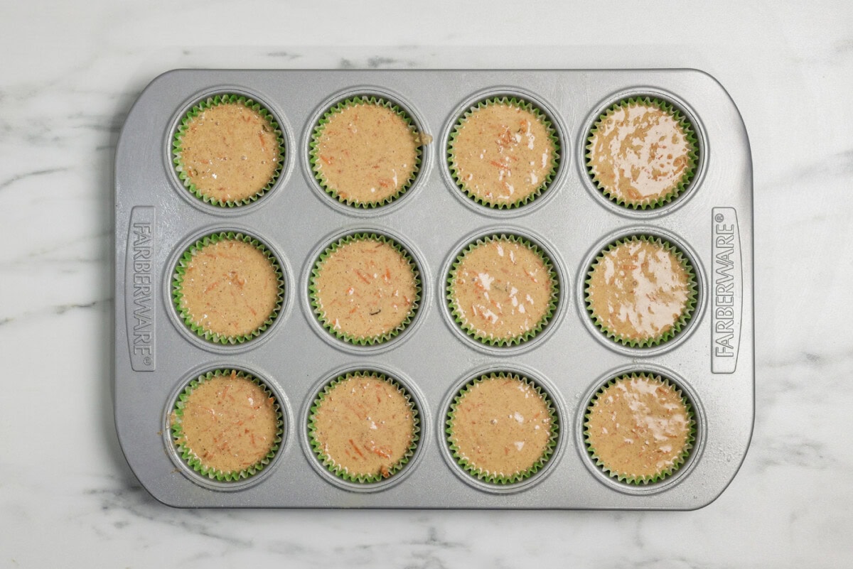 carrot cupcake batter in a muffin tray lined with paper cupcakes liners