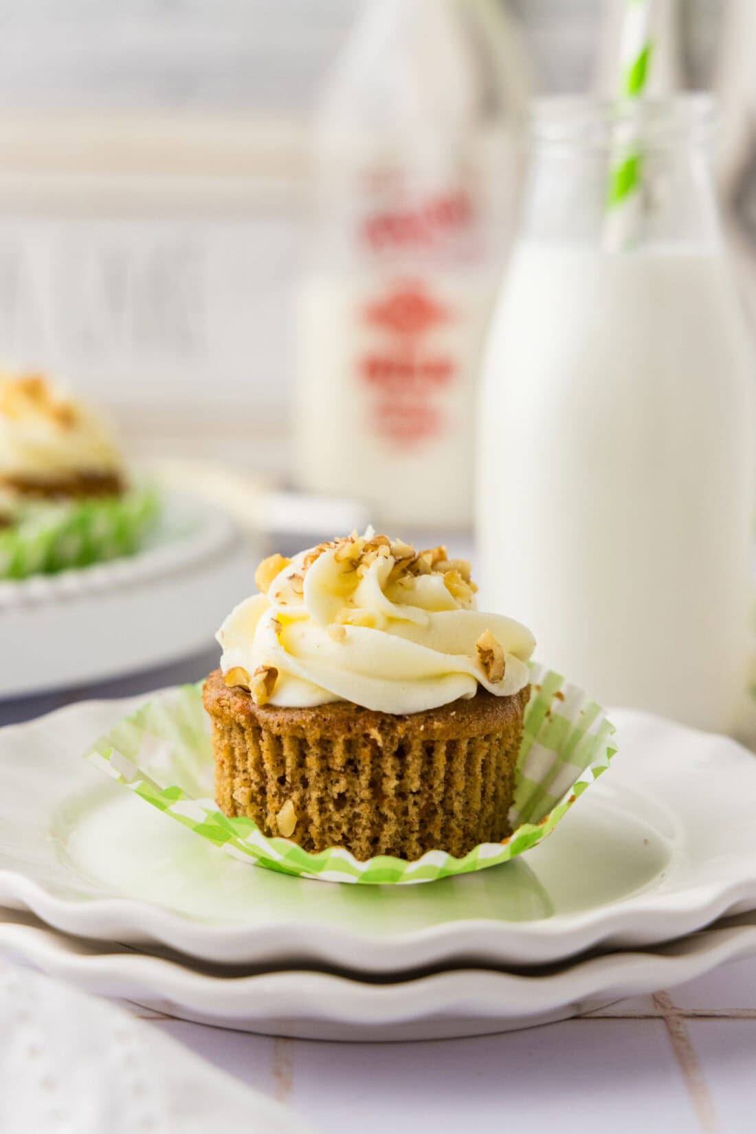 Unwrapped Carrot Cupcake on a plate with milk in the background