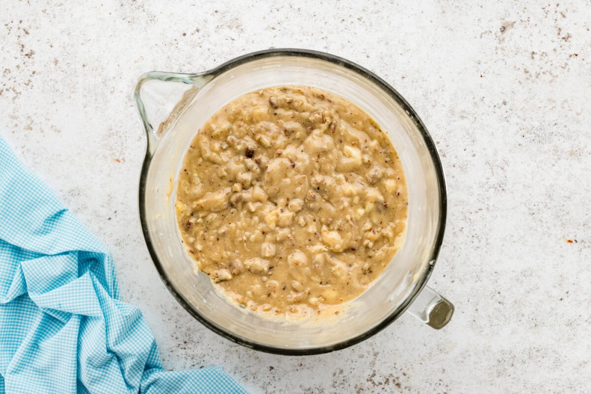 Overhead shot of cake batter with pecans and bananas in a bowl