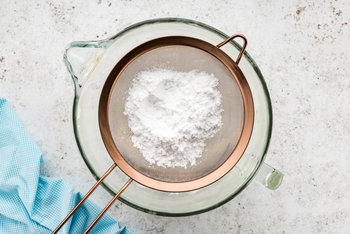 Powdered sugar in a sieve over a bowl