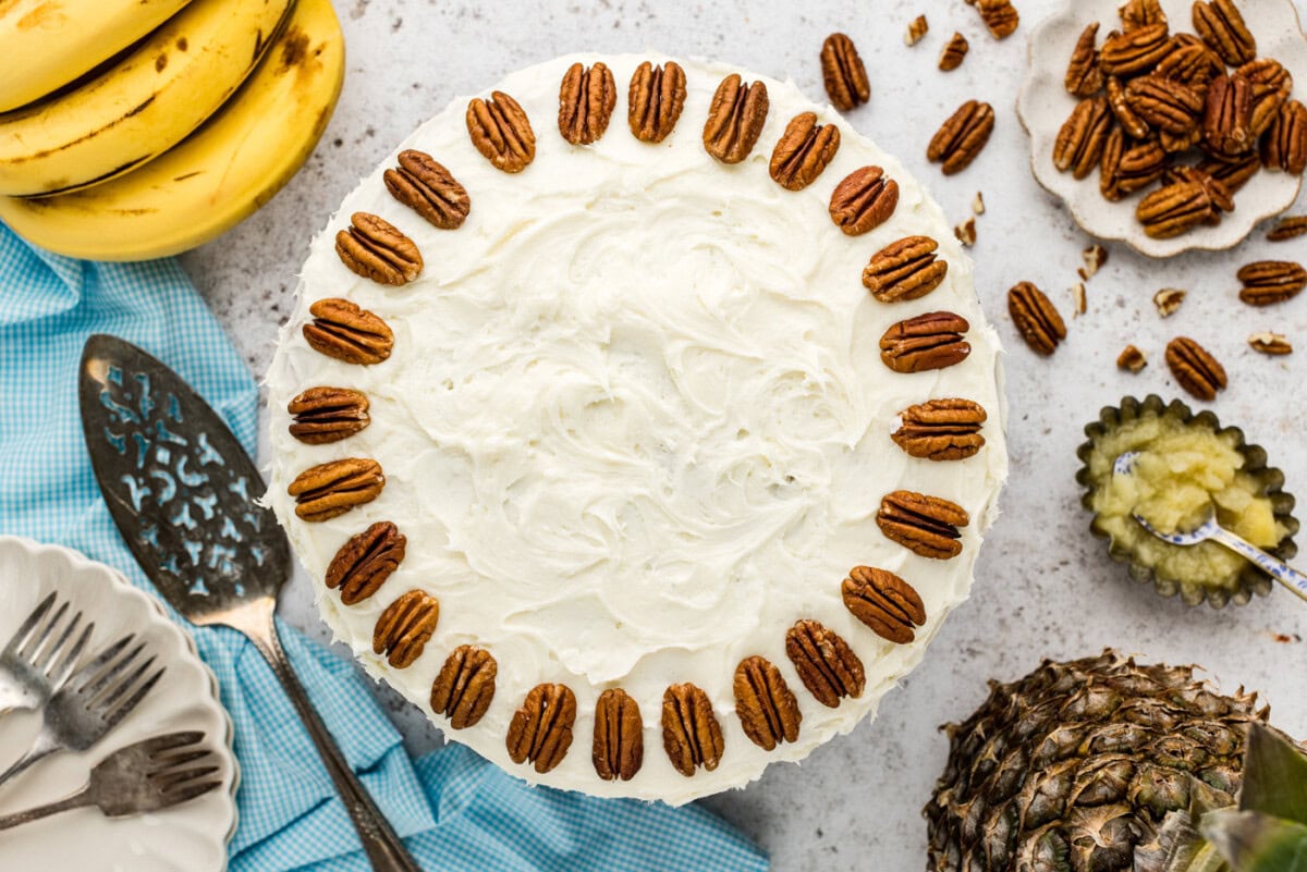 Overhead shot of hummingbird cake frosted with pecans along the perimeter