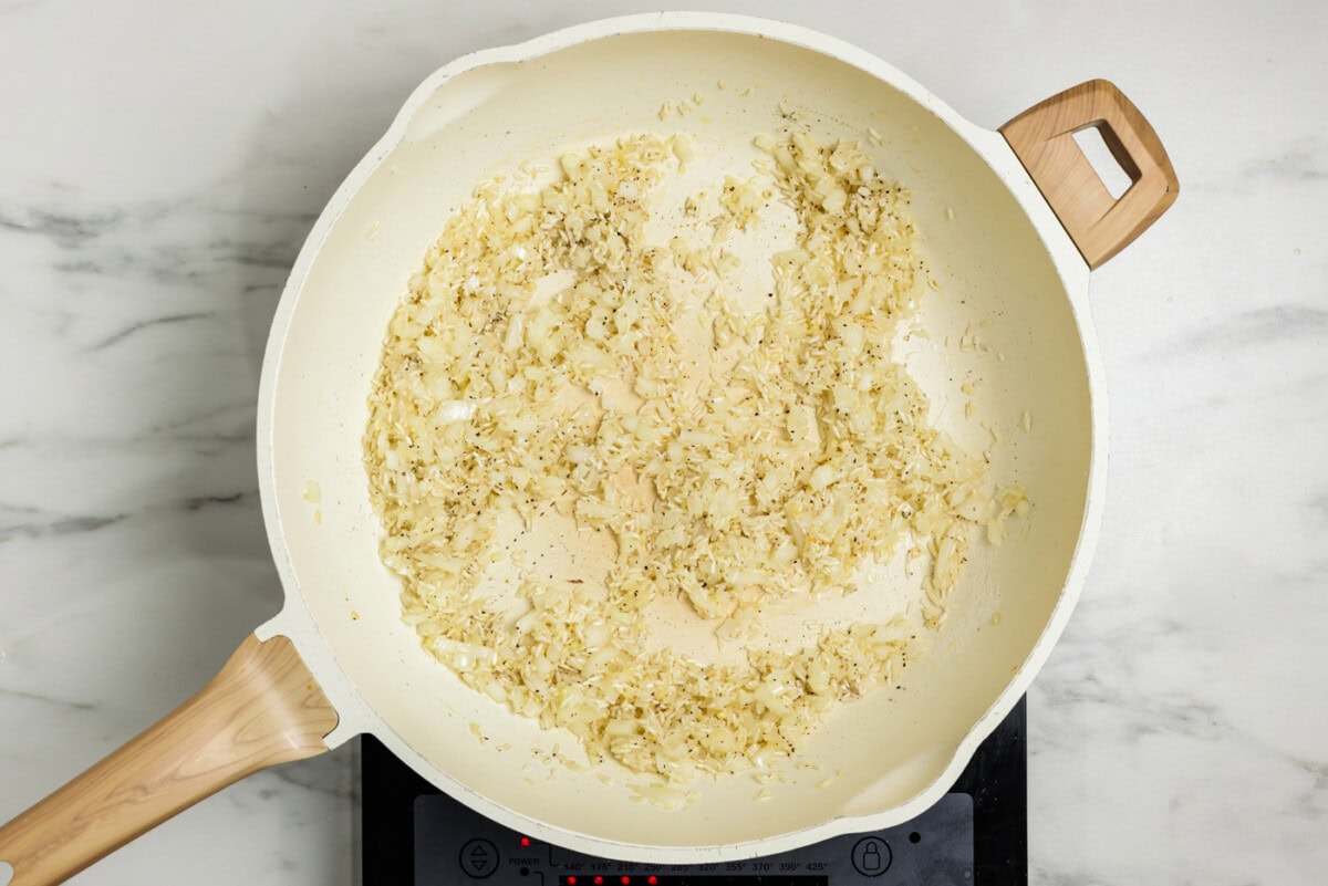 white rice cooking in skillet with onion