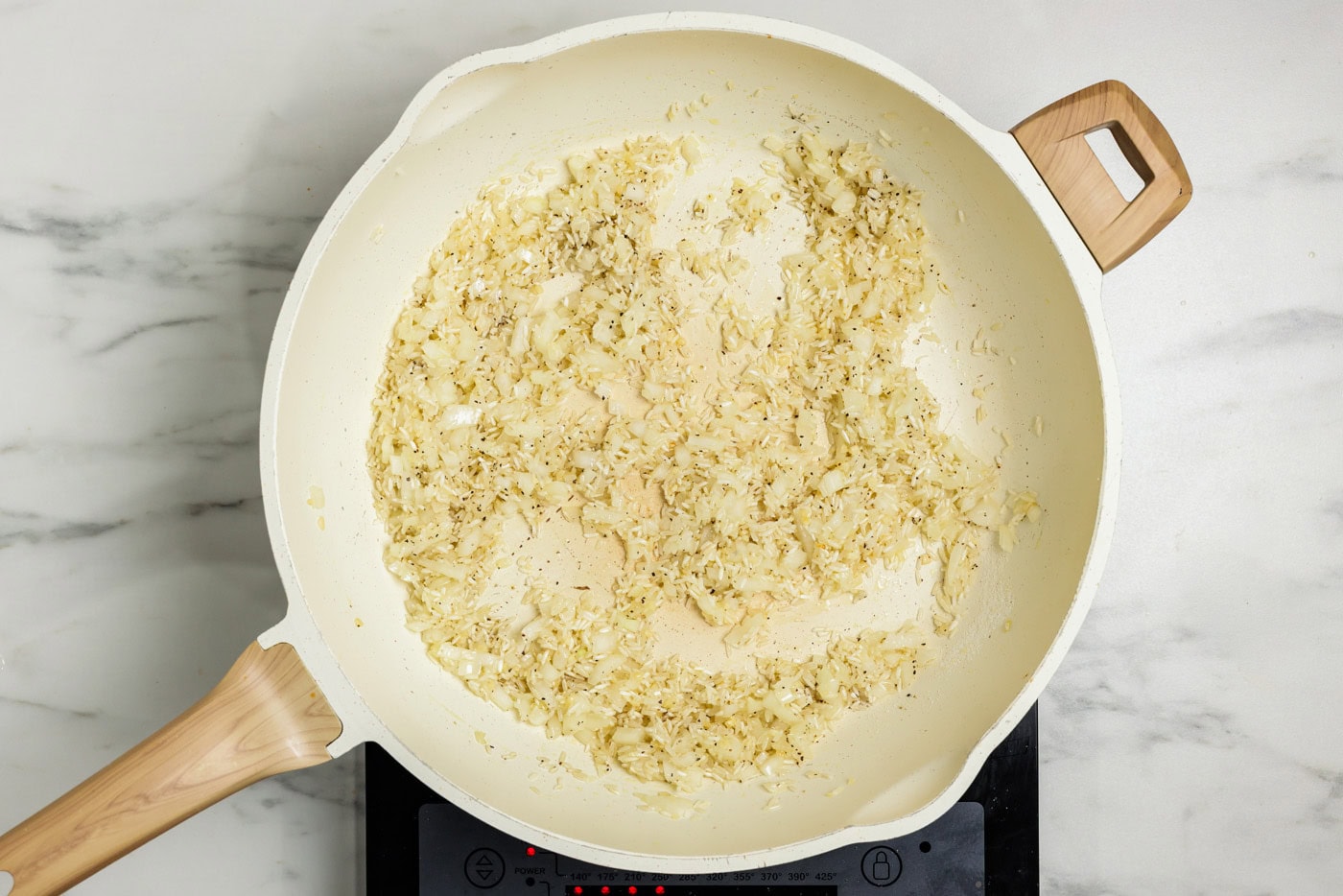 white rice cooking in skillet with onion