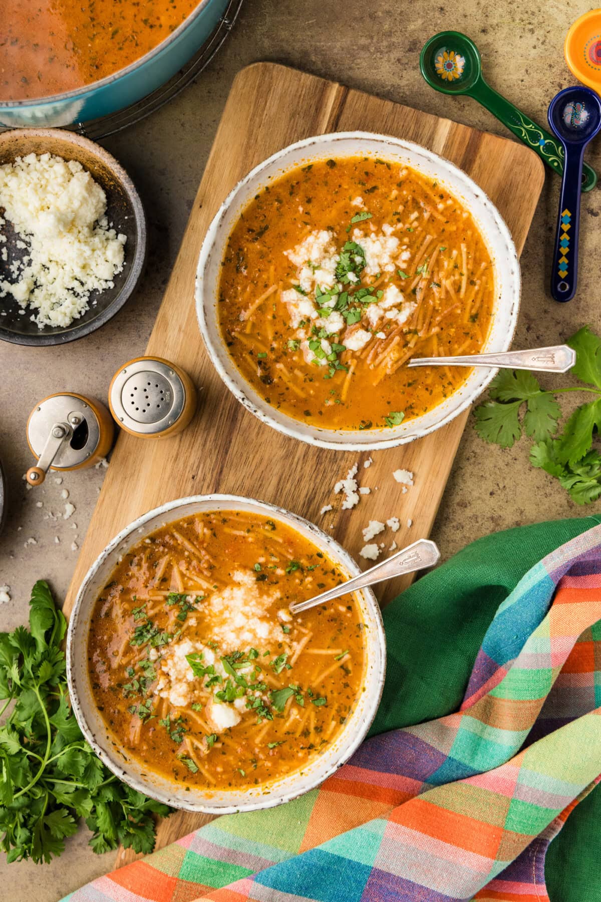 overhead photo of 2 bowls of Sopa de Fideo with cotija cheese