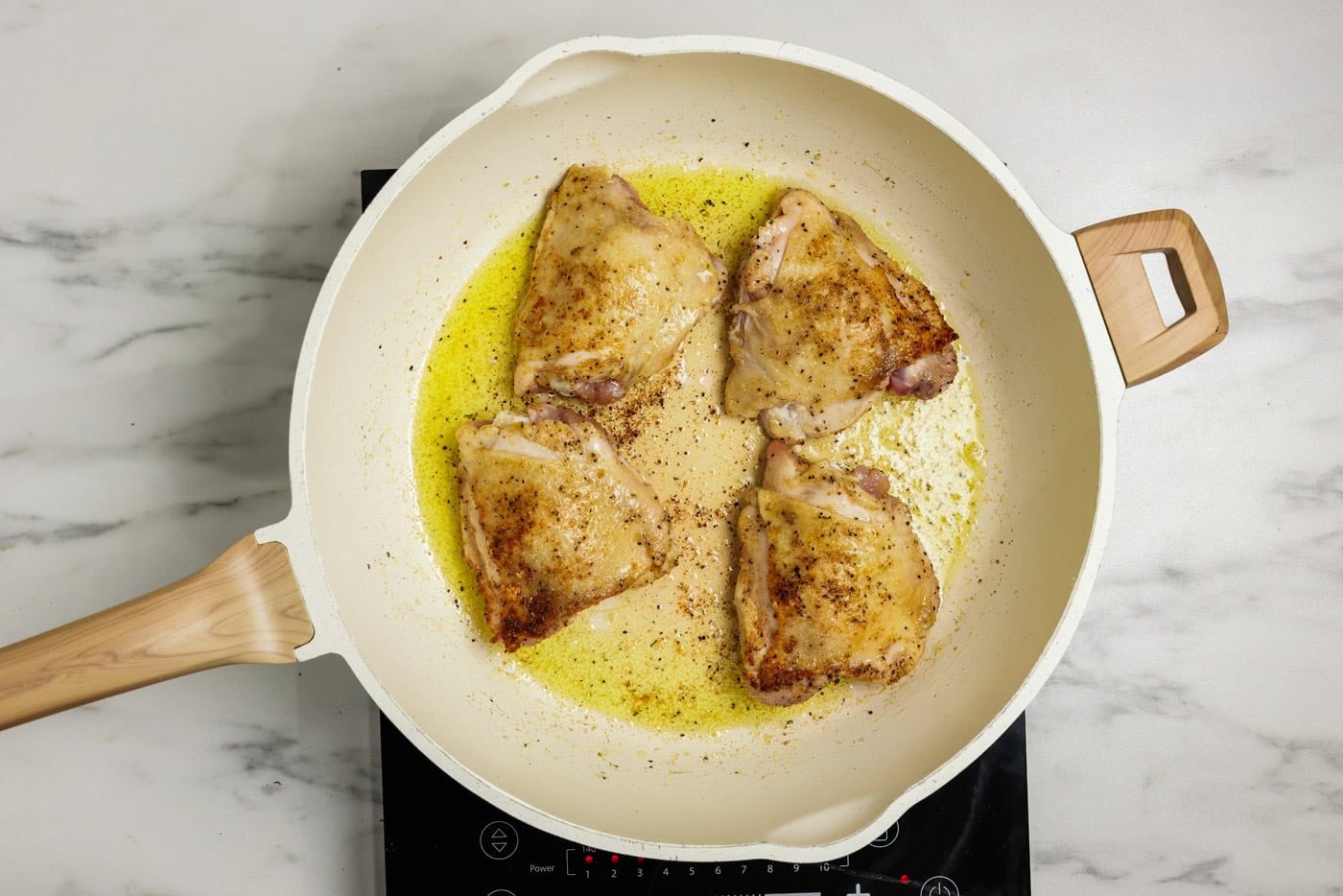 browned chicken thighs in skillet with oil