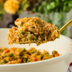 spatula lifting chicken from skillet in Arroz con Pollo dish