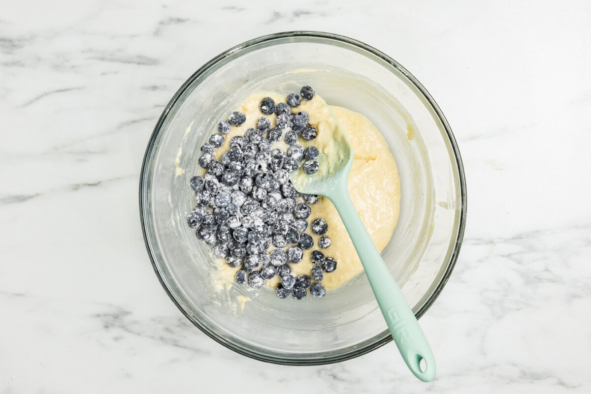 floured blueberries placed in bowl of batter