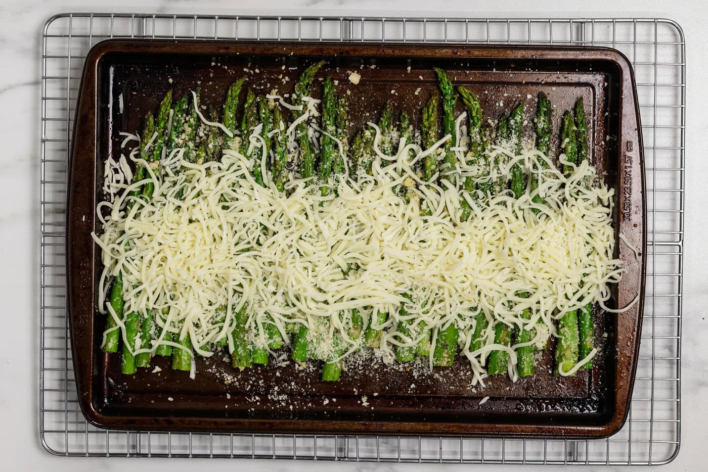 pan of asparagus with mozzarella cheese sprinkled on top