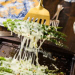 spatula lifting Cheesy Asparagus off pan