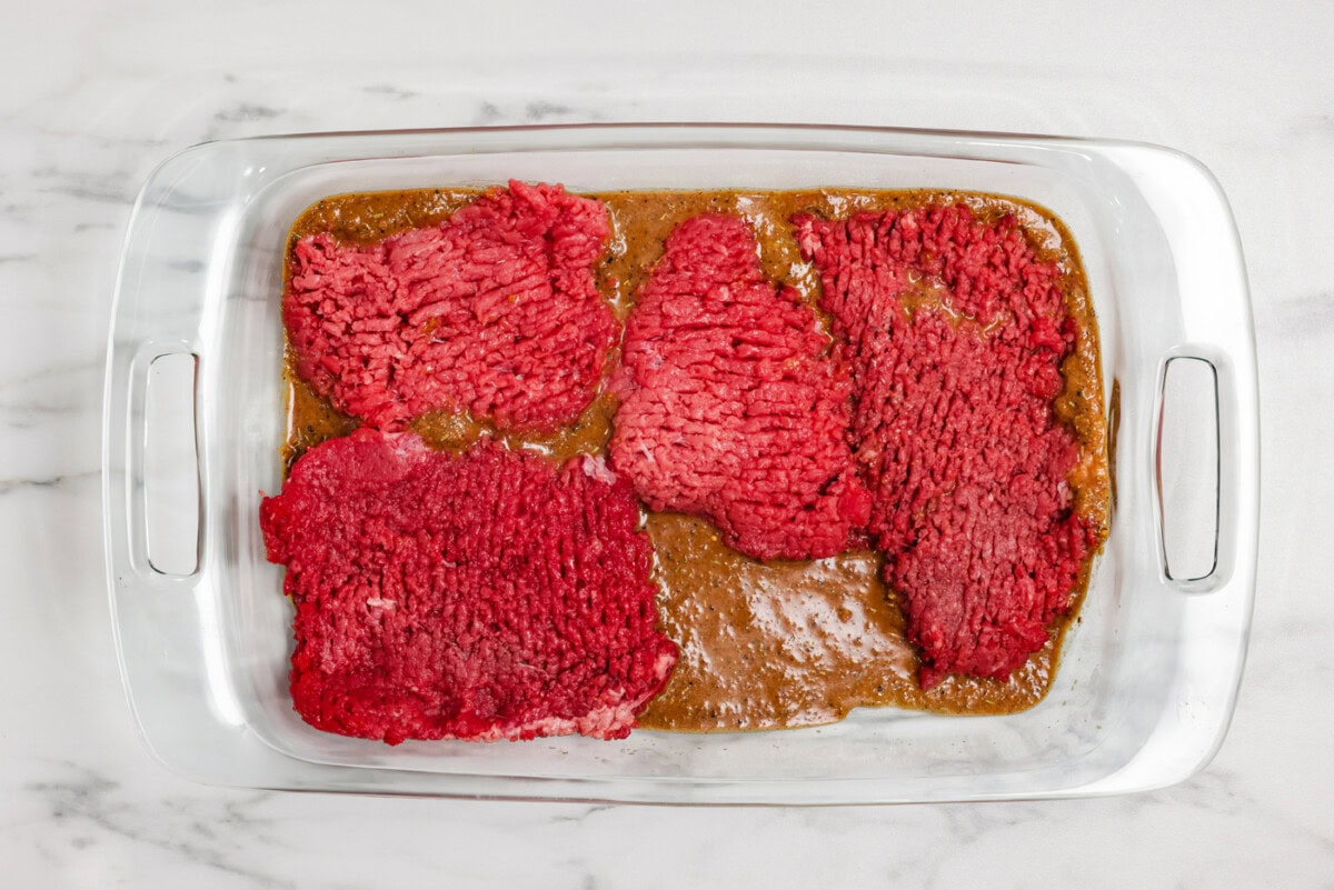 cube steaks in a dish with marinade