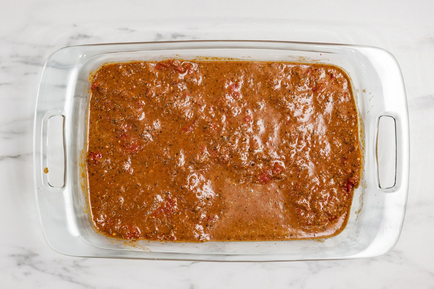 cube steak marinating in a baking dish