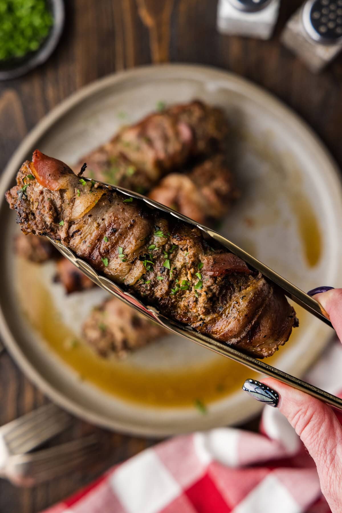 holding a Grilled Cube Steak Rollup with tongs