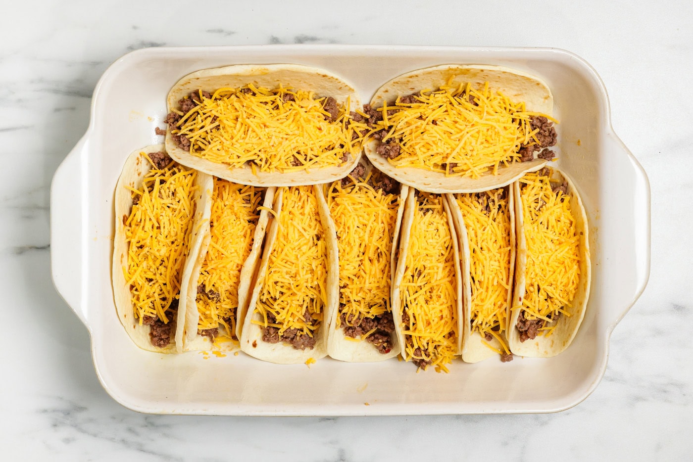 flour tortillas with taco meat and cheese in 13x9 pan