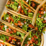 close up of tacos baked in pan in oven with toppings