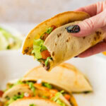 hand holding taco with bite out of it