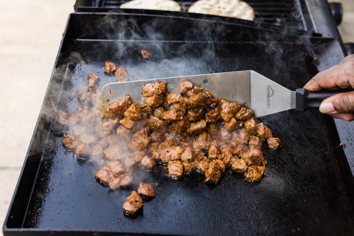 cooking steak cubes on flat top grill