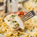 Chicken Scallopini on fettucini on plate with fork lifting a slice