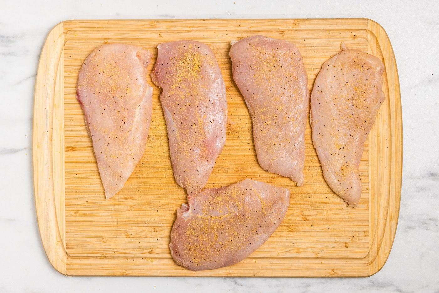 seasoned chicken breasts on board