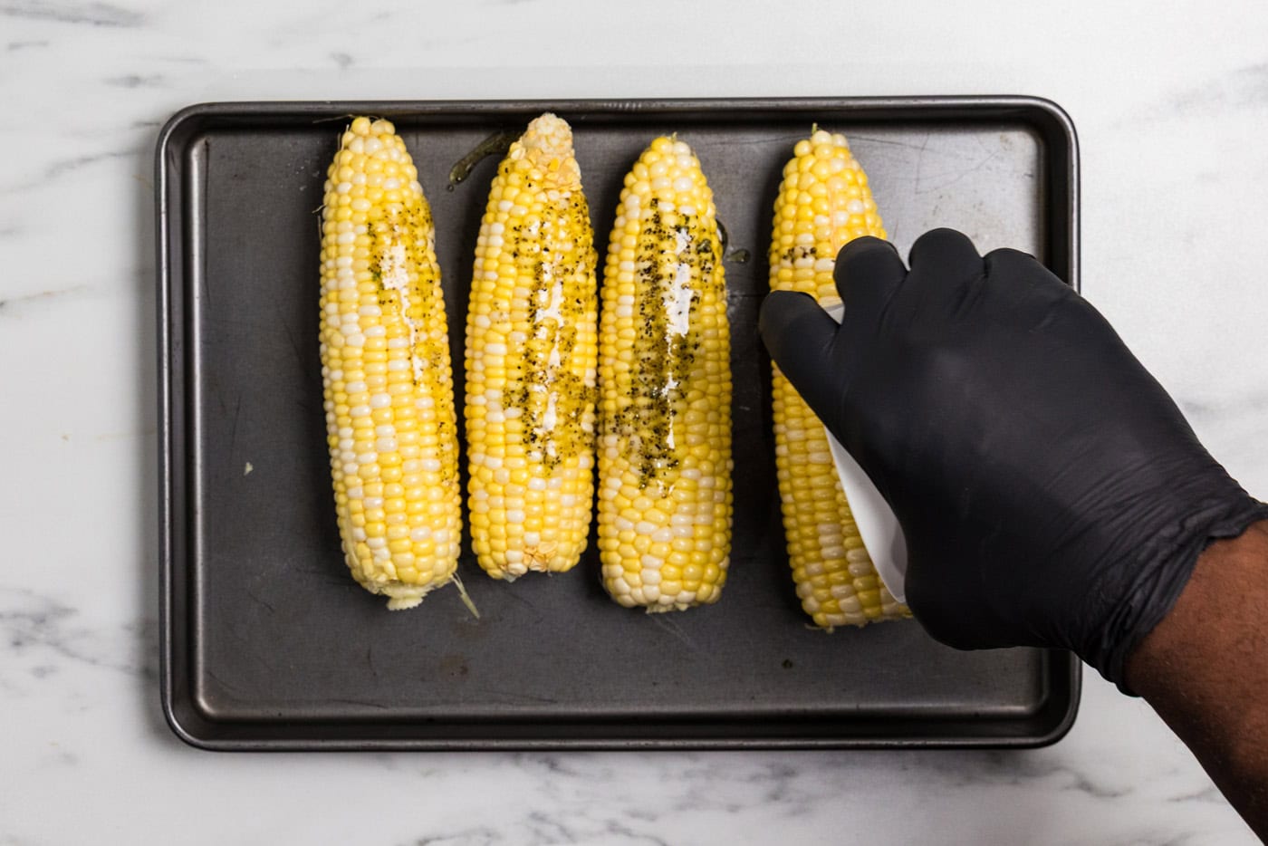 spreading seasoned oil on corn