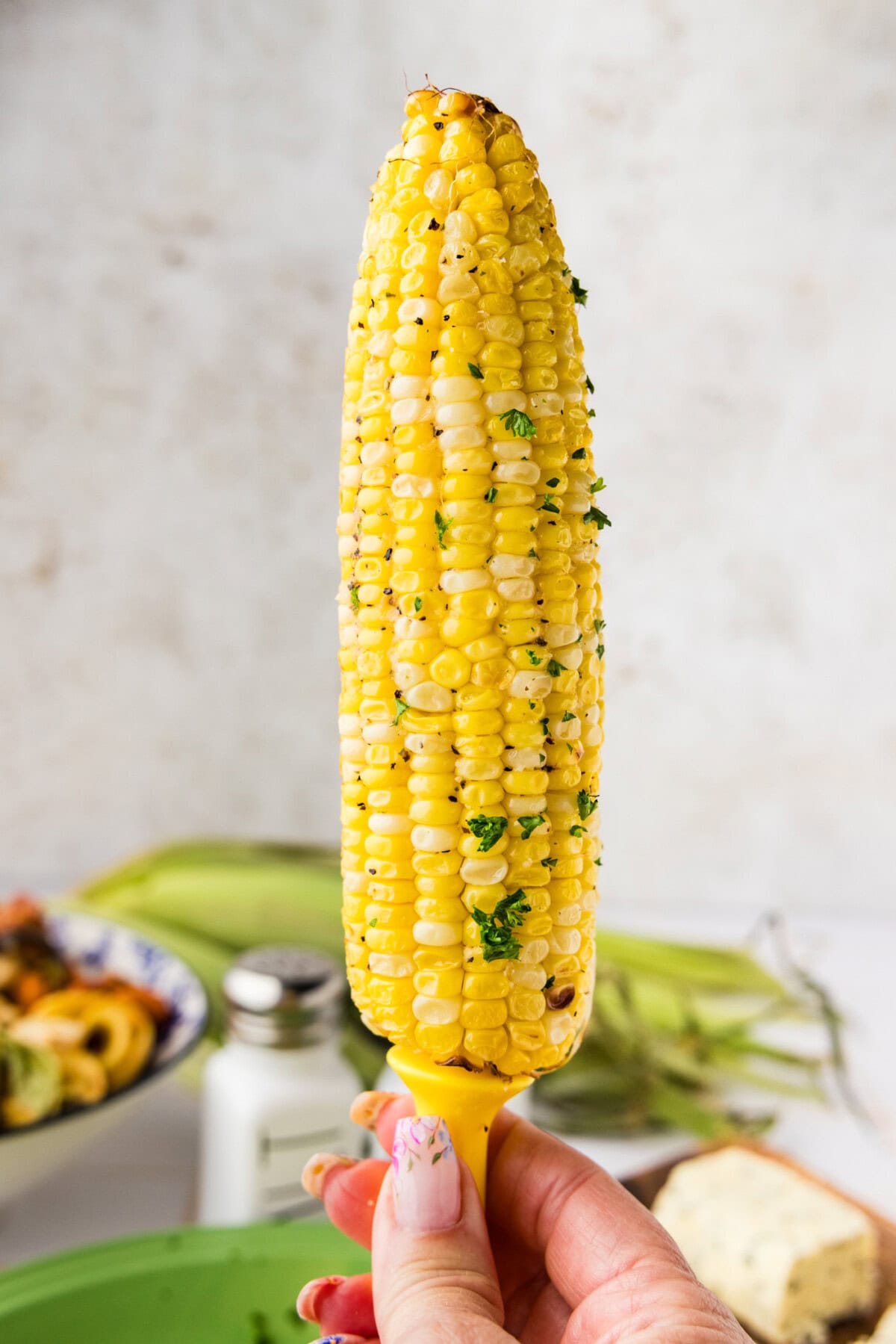 hand holding up a cob of corn