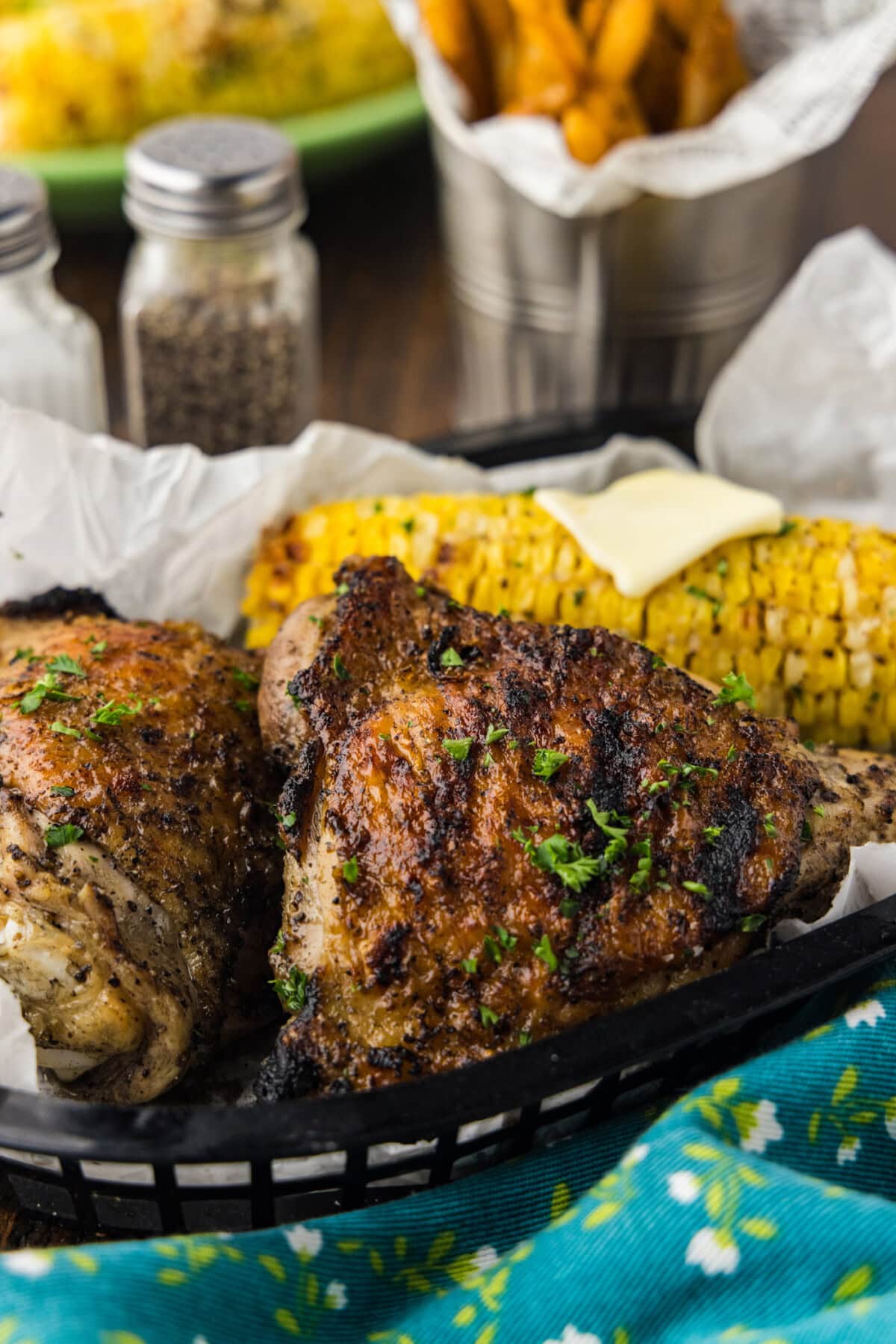 grilled chicken thighs on a plate with cor on the cob