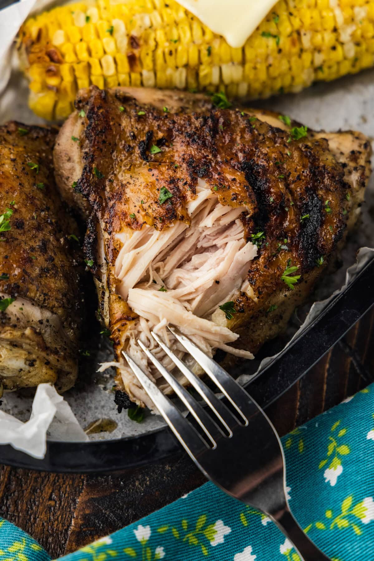 fork pulling some chicken out from a grilled chicken thigh