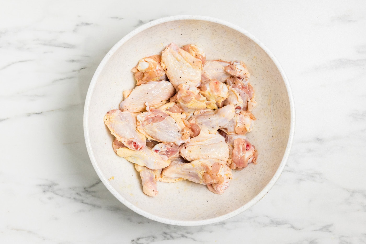 seasoned raw chicken wings in a bowl