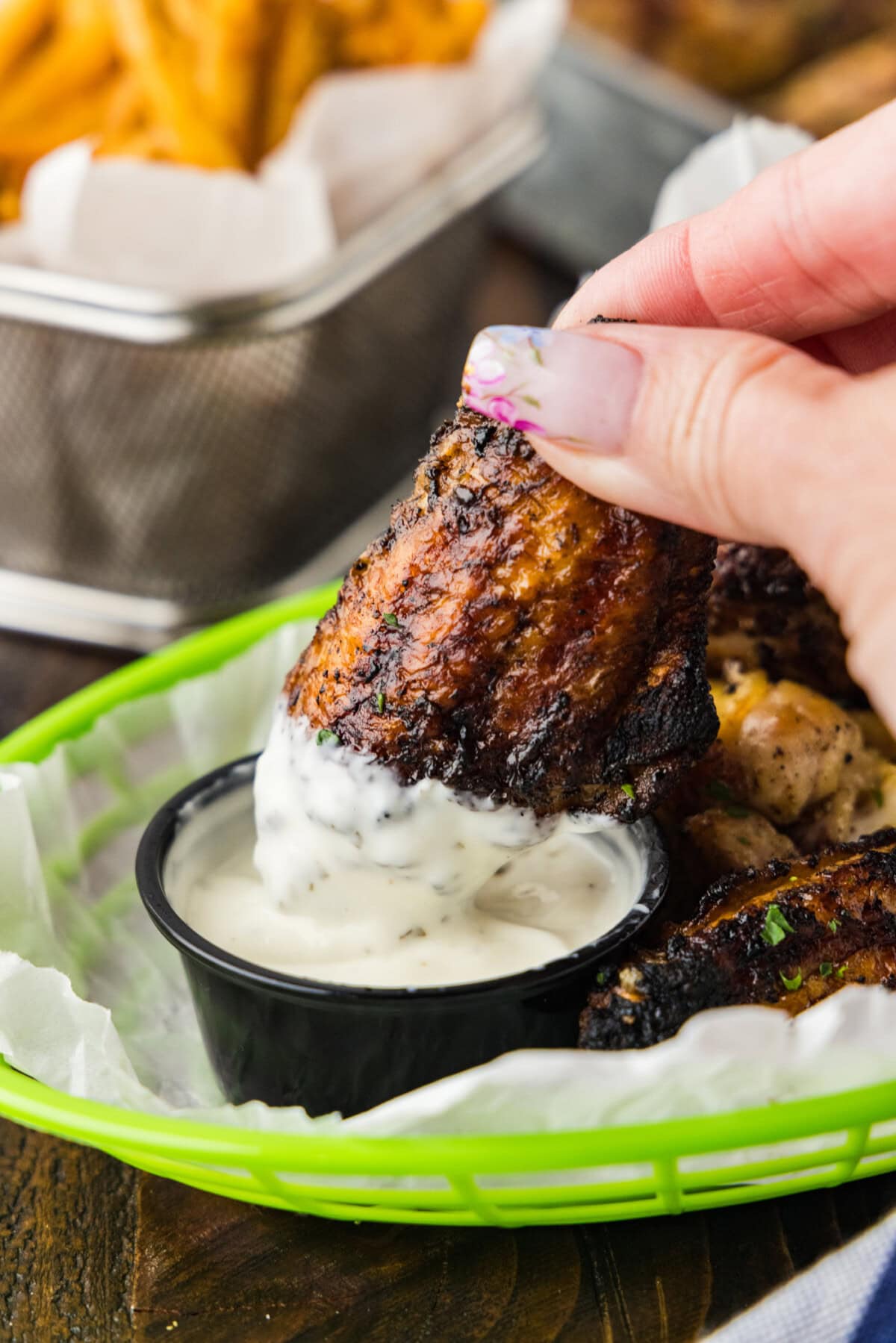 dipping a grilled chicken wing in ranch dressing