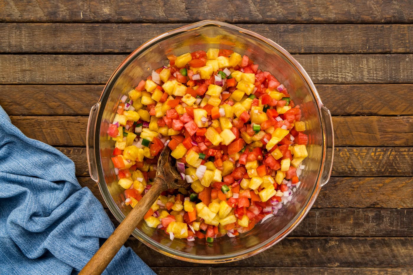 Pineapple Salsa in a glass bowl with wooden spoon