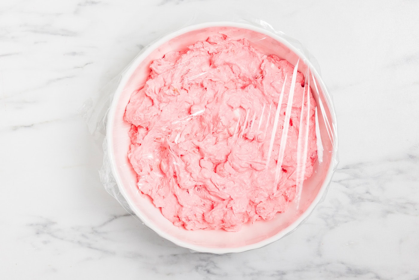 Strawberry Fluff Salad in bowl covered in plastic wrp