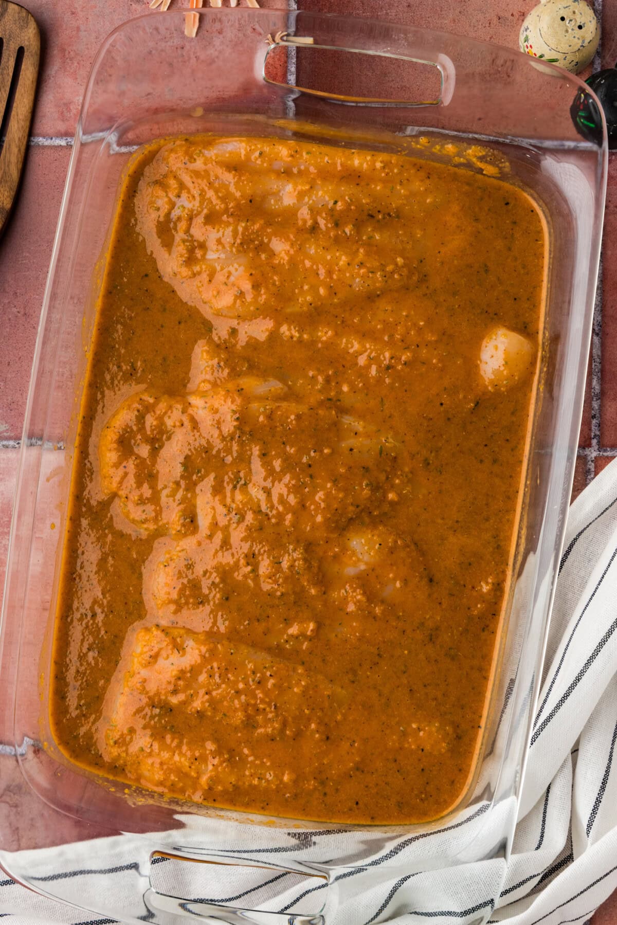 raw chicken in glass dish covered with Baja Marinade