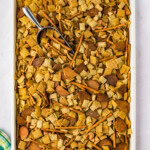overhead photo of a pan of Dill Pickle Chex Mix with a scoop